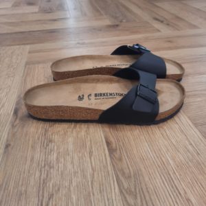 Madrid Black Regular Aîné de la famille, le modèle BIRKENSTOCK Madrid Black Regular est un vrai classique. Lancées il y a une cinquantaine d'années comme des « sandales de gymnastique », ces sandales à une bride épurées se sont peu à peu imposées comme un véritable compagnon de mode. Le dessus est en Birko-Flor®, une matière synthétique hypoallergénique et résistante. SANDALES MADRID : LES ORIGINES DE BIRKENSTOCK L’histoire du modèle Madrid remonte aux années soixante, alors que BIRKENSTOCK lançait sur le marché ses sandales au design révolutionnaire. Celui-ci fut dévoilé au salon de la chaussure de 1963 à Düsseldorf... Mais ces sandales à une bride ne connurent d’abord pas un franc succès. Inspirées par l’esthétique audacieuse du brutalisme, avec leur lit de pied souple en liège et latex et leur bride unique ajustable, elles étaient trop avant-gardistes, notamment pour la mode de l’époque qui était alors aux talons aiguilles italiens, les stilettos. Mais il n’a pas fallu longtemps aux « sandales minceur » – ainsi nommées car elles favorisent l’activation du réflexe préhenseur des orteils lors de la marche, faisant ainsi travailler les muscles des pieds et des jambes – pour se faire apprécier du public. Plus de soixante ans plus tard, ce modèle désormais appelé Madrid est l’un de nos plus grands classiques et est resté peu ou prou fidèle à l’original. Sa popularité est une véritable preuve du caractère visionnaire des designs de BIRKENSTOCK.