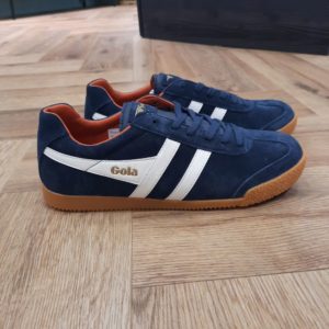 Les Gola Harrier Navy White vous donneront du style partout ! Les bandes latérales, sur lesquelles figure le nom de la marque elle-même, constituent le signe distinctif des chaussures Gola. La société Gola fabrique ses produits en Angleterre depuis 1905 et elle est toujours restée fidèle à elle-même pour ce qui est de la fonctionnalité, de la qualité et du design. Le bord rembourré est confortable et évite les points de pression. Les chaussures sont adaptées à de nombreuses activités et assurent une bonne adhérence grâce à la semelle en caoutchouc nervuré. Les chaussures se ferment avec des lacets et sont en pur cuir suédé et fin. Le look vintage convient toujours, avec un jean ou un short décontracté, ou alors en mélangeant les styles avec un pantalon à pinces et une chemise. Les baskets Gola Harrier Suede sont solides et ont un joli look à la fois sportif et intemporel ! La marque Gola est une marque principalement connue pour ses chaussures de sport. Elle a été créé en 1905 à Leicester, au Royaume Uni. Pour l'anecdote, personne ne sait exactement d'où vient le nom de la marque. Pourtant, une légende urbaine raconte qu'elle doit son nom à l'anagramme du mot "Goal" (qui signifie "but" en anglais). La marque commence à être connue à la fin des années 1960. Notamment dans le sport notamment avec la Harrier qui reste aujourd'hui encore le modèle phare de la marque anglaise. En effet, elle a très vite été adoptée par le grand public. Fort de son histoire, la marque a su traverser les générations et est aujourd'hui une marque streetwear à part entière qui sait innover et suivre les tendances. On a d'ailleurs pu voir une collection 100 % vegan sortir des tuyaux en 2019, preuve de la capacité de Gola à s'adapter au marché actuel !