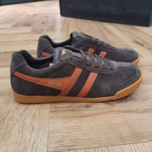 Gola Harrier Brown Orange Les Gola Harrier Brown Orange vous donneront du style partout ! Les bandes latérales, sur lesquelles figure le nom de la marque elle-même, constituent le signe distinctif des chaussures Gola. La société Gola fabrique ses produits en Angleterre depuis 1905 et elle est toujours restée fidèle à elle-même pour ce qui est de la fonctionnalité, de la qualité et du design. Le bord rembourré est confortable et évite les points de pression. Les chaussures sont adaptées à de nombreuses activités et assurent une bonne adhérence grâce à la semelle en caoutchouc nervuré. Les chaussures se ferment avec des lacets et sont en pur cuir suédé et fin. Le look vintage convient toujours, avec un jean ou un short décontracté, ou alors en mélangeant les styles avec un pantalon à pinces et une chemise. Les baskets Gola Harrier Suede sont solides et ont un joli look à la fois sportif et intemporel ! La marque Gola est une marque principalement connue pour ses chaussures de sport. Elle a été créé en 1905 à Leicester, au Royaume Uni. Pour l'anecdote, personne ne sait exactement d'où vient le nom de la marque. Pourtant, une légende urbaine raconte qu'elle doit son nom à l'anagramme du mot "Goal" (qui signifie "but" en anglais). La marque commence à être connue à la fin des années 1960. Notamment dans le sport notamment avec la Harrier qui reste aujourd'hui encore le modèle phare de la marque anglaise. En effet, elle a très vite été adoptée par le grand public. Fort de son histoire, la marque a su traverser les générations et est aujourd'hui une marque streetwear à part entière qui sait innover et suivre les tendances. On a d'ailleurs pu voir une collection 100 % vegan sortir des tuyaux en 2019, preuve de la capacité de Gola à s'adapter au marché actuel !