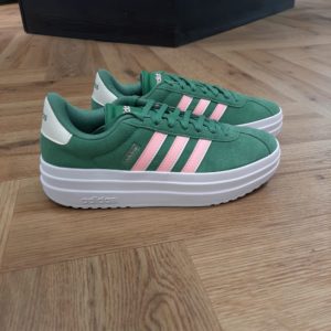 Adidas VL Court Bold Green Une chaussure compensée au style polyvalent. Tout est une question d'équilibre avec cette chaussure adidas VL Court Bold Green. En effet, elle présente un design épuré mais avec une semelle compensée qui sublime tout le look et te donne de la hauteur. Pour commencer, sa tige est en cuir. Puis, sa doublure textile et sa semelle extérieure en caoutchouc résistant s'associent pour t'offrir un confort ultime au quotidien. La marque C'est le 18 août 1949 qu'Adi Dassler a démarré l'aventure adidas, avec pour objectif d'améliorer les performances des athlètes. 70 ans plus tard, adidas a laissé sa marque sur le monde du sport, mais aussi celui de la mode, de la musique, de la culture, du développement durable et bien d'autres encore. Voyage avec nous à travers le temps et découvre l'histoire d'adidas avec des modèles qui ont influencé le lifestyle d'aujourd'hui. Juste après la naissance officielle des 3 bandes en 1949, les années 50 ont connu un véritable boom technologique avec des équipements innovants pour les athlètes de classe mondiale. Ainsi, c'est pendant cette décennie qu'est apparue la Samba, toujours portée de nos jours pas les joueurs de Five et de futsal, et toujours présente dans la rue. Pendant les 50's, adidas a développé une chaussure de sprint qui a battu un record du monde et la première chaussure de football conçue avec une semelle en nylon, marquant une vraie nouveauté en termes de confort et de sensations. D'autres modèles ont vu le jour durant cette période, comme la chaussure de basketball Allround, devenue une véritable icône dans les 80's. Ces années ont été révolutionnaires, créant un véritable avant et après pour les sportifs de haut niveau. Mais ce n'était que le début de l'histoire d'adidas.