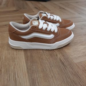 Vans Hylane Marron En effet, les Vans Hylane Marron s'inspirent du skate de l'an 2000. Elles remettent au goût du jour notre silhouette Upland datant de 1999. Ces clins d'œil au passé se conjuguent aux détails esthétiques tels que la Sidestripe 3D satinée et les logos brodés. Tandis, que la silhouette épaisse et la languette de skate rembourrée leur confèrent une allure et une sensation rétro. Enfin, elles sont dotées d'une semelle concave et de la texture unique des V imbriqués. Les chaussures Hylane font de l'esthétique old school un essentiel de ta garde-robe actuelle. Pour conclure, passé et présent se rejoignent dans cette chaussure inspirée des années 2000. La marque C’est en 1966 que Paul, accompagné de son frère Jim et de ses amis Gordy et Serge, ouvre les portes de la Van Doren Rubber Company au 704 East Broadway à Anaheim, en Californie. Leur façon de travailler est alors unique, vendant leurs chaussures d’où elles sont fabriquées. « Des baskets en toile pour toute la famille » tel était le slogan qu’affichaient les boîtes à chaussures à l’époque. C’est le principe novateur de la Van Doren Rubber Company, fondée par ces deux frères originaires de Boston : produire à la commande et sur place, dans la petite usine qui jouxte les 40 m2 du magasin. Et vendre en direct cette chaussure en toile robuste reposant sur une semelle gaufrée en caoutchouc vulcanisé et antidérapante.  Hélas, cette sneaker disparaît brutalement des radars avec la faillite de Vans en 1983. Mais l’histoire de Vans n’écrivait pas son point final. Elle mettra vingt ans à redevenir le signe extérieur d’appartenance à la religion du cool, aux pieds des rockers, des grands ados et des stars d'Hollywood (Justin Bieber, Zac Efron, Harry Styles…). À bientôt 60 ans, cet indéboulonnable totem de la culture skate est aujourd’hui un classique du dressing estival porté flambant neuf à un mariage ou en fin de vie à la plage. Avant de les renouveler les yeux fermés…