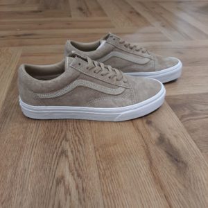 Old Skool Beige La chaussure emblématique qui a donné vie à notre Sidestripe : Voici les Old Skool Les Old Skool Beige ont été les premières chaussures à arborer la fameuse Sidestripe de Vans, même s'il ne s'agissait à l'époque que d'un simple gribouillis dessiné par le fondateur Paul Van Doren. Ce modèle de chaussure basse s'est imposé depuis ses débuts en 1977 comme une icône dans les milieux du skate, de la musique et de la mode. Des fans de skate et de punk des années 90 aux légendes actuelles du hip-hop et de la mode, les Old Skool restent une référence des esprits libres et créatifs. La tige élégante en daim confère à ce modèle un caractère unique. La marque C’est en 1966 que Paul, accompagné de son frère Jim et de ses amis Gordy et Serge, ouvre les portes de la Van Doren Rubber Company au 704 East Broadway à Anaheim, en Californie. Leur façon de travailler est alors unique, vendant leurs chaussures d’où elles sont fabriquées. « Des baskets en toile pour toute la famille » tel était le slogan qu’affichaient les boîtes à chaussures à l’époque. C’est le principe novateur de la Van Doren Rubber Company, fondée par ces deux frères originaires de Boston : produire à la commande et sur place, dans la petite usine qui jouxte les 40 m2 du magasin. Et vendre en direct cette chaussure en toile robuste reposant sur une semelle gaufrée en caoutchouc vulcanisé et antidérapante.  Hélas, cette sneaker disparaît brutalement des radars avec la faillite de Vans en 1983. Mais l’histoire de Vans n’écrivait pas son point final. Elle mettra vingt ans à redevenir le signe extérieur d’appartenance à la religion du cool, aux pieds des rockers, des grands ados et des stars d'Hollywood (Justin Bieber, Zac Efron, Harry Styles…). À bientôt 60 ans, cet indéboulonnable totem de la culture skate est aujourd’hui un classique du dressing estival porté flambant neuf à un mariage ou en fin de vie à la plage. Avant de les renouveler les yeux fermés…