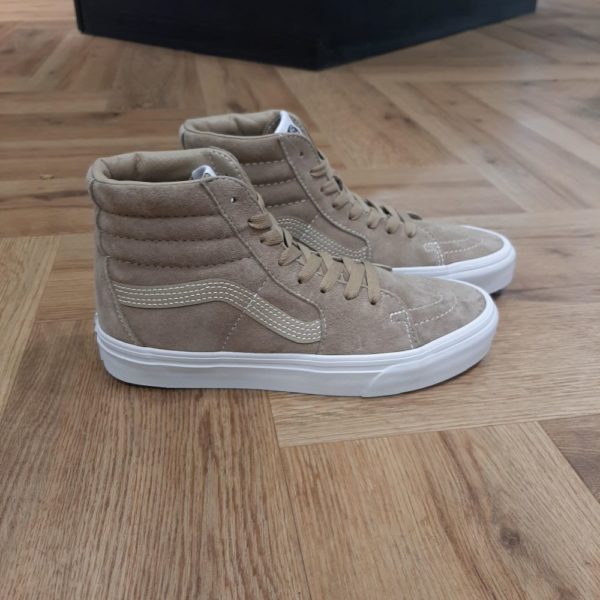 Sk8 Hi Beige Les légendaires chaussures montantes qui ont changé la donne depuis 1978 Les Sk8 Hi Beige sont les premières chaussures montantes à faire leur apparition sur la scène du skate. Tout d'abord, elle possède un col rembourré pour soutenir la cheville et des embouts renforcés. Ces chaussures restent une référence en matière de style. Ces Sk8-Hi sont le deuxième modèle à présenter la Sidestripe de Vans. Son design audacieux n'a jamais perdu son caractère emblématique. La tige en daim de porc apporte une touche d'originalité à cette version des Sk8-Hi culte. La marque C’est en 1966 que Paul, accompagné de son frère Jim et de ses amis Gordy et Serge, ouvre les portes de la Van Doren Rubber Company au 704 East Broadway à Anaheim, en Californie. Leur façon de travailler est alors unique, vendant leurs chaussures d’où elles sont fabriquées. « Des baskets en toile pour toute la famille » tel était le slogan qu’affichaient les boîtes à chaussures à l’époque. C’est le principe novateur de la Van Doren Rubber Company, fondée par ces deux frères originaires de Boston : produire à la commande et sur place, dans la petite usine qui jouxte les 40 m2 du magasin. Et vendre en direct cette chaussure en toile robuste reposant sur une semelle gaufrée en caoutchouc vulcanisé et antidérapante.  Hélas, cette sneaker disparaît brutalement des radars avec la faillite de Vans en 1983. Mais l’histoire de Vans n’écrivait pas son point final. Elle mettra vingt ans à redevenir le signe extérieur d’appartenance à la religion du cool, aux pieds des rockers, des grands ados et des stars d'Hollywood (Justin Bieber, Zac Efron, Harry Styles…). À bientôt 60 ans, cet indéboulonnable totem de la culture skate est aujourd’hui un classique du dressing estival porté flambant neuf à un mariage ou en fin de vie à la plage. Avant de les renouveler les yeux fermés…