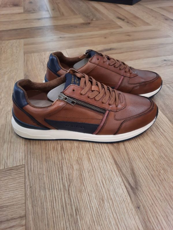 Redskins Callias Cognac Les baskets en cuir Redskins Callias Cognac allient style moderne et confort optimal. Tout d'abord, elles sont fabriquées en cuir de qualité. Elles sont dotées d'une doublure en cuir et textile favorisant la respirabilité. Puis, la semelle intérieure, également confectionnée en cuir et textile, offre un bon amorti, tandis que la semelle extérieure en caoutchouc assure une excellente adhérence. Ce modèle se distingue par sa fermeture combinée : lacets et zip, garantissant un ajustement personnalisé et un enfilage et un retrait faciles. Avec leur design urbain, ces baskets sont parfaites pour compléter une tenue décontractée tout en ajoutant une touche de caractère. Que ce soit pour une journée en ville ou une journée active, les baskets REDSKINS sont le choix idéal pour celles qui recherchent l'authenticité et l'élégance dans leur style. Les Baskets REDSKINS Adeptes des sneakers ? En quête de la paire idéale pour un look casual et sportswear ? Vous êtes au bon endroit ! Véritable incontournable du vestiaire masculin, la basket s'impose comme la chaussure à la fois pratique et stylée par excellence. REDSKINS propose des baskets pour hommes dans différentes matières comme le velours, le nubuck et le cuir pour un style tendance. Que vous recherchiez un style décontracté ou une allure plus habillée, nos baskets sauront répondre à vos envies. Confortables, robustes et élégantes, elles deviendront rapidement vos alliées du quotidien. Matériaux, formes, semelles, les baskets sont un véritable atout mode ! Elle n’a de cesse de se réinventer à chaque saison, c’est un intemporel qui allie confort et style. Quelle que soit la matière choisie, il convient de bien les entretenir pour éviter qu’elles ne se détériorent rapidement. Il ne faut pas hésiter à les essuyer régulièrement avec une brosse souple pour faciliter leur entretien. Les sneakers en cuir sont aujourd’hui considérées comme de véritables chaussures de ville. Les baskets en cuir sont faciles à porter et conviennent à toutes les tailles, car certains modèles sont disponibles en grandes pointures. Ces chaussures pour homme sont aussi adaptées en toute saison, même pendant la saison automne-hiver, car elles confèrent une bonne isolation.