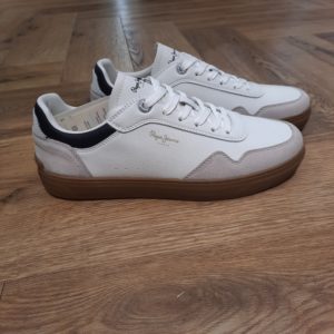 Chaussures Camden Collar Beige Les Chaussures Camden Collar Beige sont des baskets avec des pièces en cuir, une semelle en caoutchouc avec la marque, une semelle intérieure amovible et thermoformée et un logo classique sur le côté. Histoire. En 1973, trois frères Nitin Shah, Arun Shah et Milan Shah, ouvrent une petite « jeanerie » sur le marché de Portobello Road, à l'ouest de Londres, afin de vendre leurs créations. Les frères Shah rencontrent un franc succès, si bien qu'en 1975 ils possèdent quatre boutiques à travers la capitale londonienne. Nous sommes une marque emblématique, synonyme de denim et d'une créativité sans limites . Pepe Jeans London vous offre les bases pour rayonner de confiance en vous, d'unicité et d'authenticité. Dans les années 80, Pepe Jeans est numéro un du marché anglais du jean, devançant ses concurrents américains. C'est ainsi que la marque s’attaque à l’international; aux États-Unis pour commencer où elle implante des bureaux et y ouvre une boutique (1984). L'entreprise Pepe Jeans a ensuite été rachetée par l'espagnol Vicente Castellano en 1989. Les années 1980 seront des années de développement pour l'entreprise. De célèbres groupes tels que les Smiths entrent sous contrat avec la marque pour des campagnes de pub. En 1992, Pepe Jeans introduit son logo actuel.