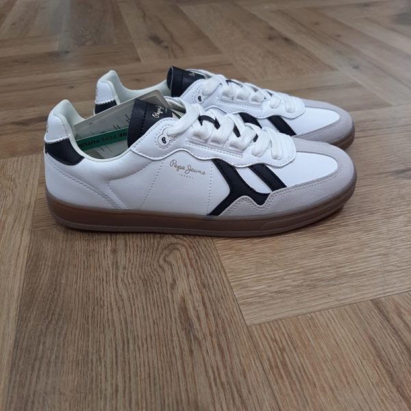 Pepe Jeans Ball Class Les baskets Pepe Jeans Ball Class sont des baskets de sport avec des pièces en daim de vache et en cuir recyclé, concept de contraste de couleur, isotipe iconique sur le côté, col rembourré, œillet personnalisé avec le logo du monogramme « P », logo de 1973 sur la languette du talon, logo classique sur le côté et semelle en caoutchouc translucide avec la marque. Histoire de la marque En 1973, trois frères Nitin Shah, Arun Shah et Milan Shah, ouvrent une petite « jeanerie » sur le marché de Portobello Road, à l'ouest de Londres, afin de vendre leurs créations. Les frères Shah rencontrent un franc succès, si bien qu'en 1975 ils possèdent quatre boutiques à travers la capitale londonienne. Nous sommes une marque emblématique, synonyme de denim et d'une créativité sans limites . Pepe Jeans London vous offre les bases pour rayonner de confiance en vous, d'unicité et d'authenticité. Dans les années 80, Pepe Jeans est numéro un du marché anglais du jean, devançant ses concurrents américains. C'est ainsi que la marque s’attaque à l’international; aux États-Unis pour commencer où elle implante des bureaux et y ouvre une boutique (1984). L'entreprise Pepe Jeans a ensuite été rachetée par l'espagnol Vicente Castellano en 1989. Les années 1980 seront des années de développement pour l'entreprise. De célèbres groupes tels que les Smiths entrent sous contrat avec la marque pour des campagnes de pub. En 1992, Pepe Jeans introduit son logo actuel.