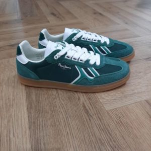 Description Pepe Jeans Sneakers Ball - Baskets multi-matières - Détails en daim sur l'embout, la bande d'œillets et le talon - Fermeture à lacets avec anneaux en forme de D - Logo PEPE JEANS thermocollé sur le côté - Œillet personnalisé avec monogramme P - Talon métallisé aux couleurs contrastées avec logo 1973 - Semelle extérieure en caoutchouc translucide - Dimensions : 29,5 cm x 10 cm x 6,8 cm Les baskets Pepe Jeans Sneakers Ball sont des baskets avec des pièces en cuir, une semelle en caoutchouc avec la marque, une semelle intérieure amovible et thermoformée et un logo classique sur le côté. Histoire. En 1973, trois frères Nitin Shah, Arun Shah et Milan Shah, ouvrent une petite « jeanerie » sur le marché de Portobello Road, à l'ouest de Londres, afin de vendre leurs créations. Les frères Shah rencontrent un franc succès, si bien qu'en 1975 ils possèdent quatre boutiques à travers la capitale londonienne. Nous sommes une marque emblématique, synonyme de denim et d'une créativité sans limites . Pepe Jeans London vous offre les bases pour rayonner de confiance en vous, d'unicité et d'authenticité. Dans les années 80, Pepe Jeans est numéro un du marché anglais du jean, devançant ses concurrents américains. C'est ainsi que la marque s’attaque à l’international; aux États-Unis pour commencer où elle implante des bureaux et y ouvre une boutique (1984). L'entreprise Pepe Jeans a ensuite été rachetée par l'espagnol Vicente Castellano en 1989. Les années 1980 seront des années de développement pour l'entreprise. De célèbres groupes tels que les Smiths entrent sous contrat avec la marque pour des campagnes de pub. En 1992, Pepe Jeans introduit son logo actuel.