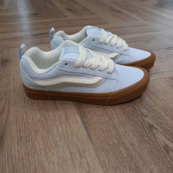Knu Skool Bleu Ciel Un modèle tout en volume d'inspiration nineties, repensé pour aujourd'hui. Les Knu Skool Bleu Ciel sont une interprétation moderne d'un style classique des années 90, définies par leur languette épaisse, leur Sidestripe moulée en 3D et leurs lacets oversize épais. Avec leur profil original et leurs détails remarquables, les Knu Skool jouent sur le modèle Old Skool originel tout en intégrant des tendances actuelles. La marque C’est en 1966 que Paul, accompagné de son frère Jim et de ses amis Gordy et Serge, ouvre les portes de la Van Doren Rubber Company au 704 East Broadway à Anaheim, en Californie. Leur façon de travailler est alors unique, vendant leurs chaussures d’où elles sont fabriquées. « Des baskets en toile pour toute la famille » tel était le slogan qu’affichaient les boîtes à chaussures à l’époque. C’est le principe novateur de la Van Doren Rubber Company, fondée par ces deux frères originaires de Boston : produire à la commande et sur place, dans la petite usine qui jouxte les 40 m2 du magasin. Et vendre en direct cette chaussure en toile robuste reposant sur une semelle gaufrée en caoutchouc vulcanisé et antidérapante.  Hélas, cette sneaker disparaît brutalement des radars avec la faillite de Vans en 1983. Mais l’histoire de Vans n’écrivait pas son point final. Elle mettra vingt ans à redevenir le signe extérieur d’appartenance à la religion du cool, aux pieds des rockers, des grands ados et des stars d'Hollywood (Justin Bieber, Zac Efron, Harry Styles…). À bientôt 60 ans, cet indéboulonnable totem de la culture skate est aujourd’hui un classique du dressing estival porté flambant neuf à un mariage ou en fin de vie à la plage. Avant de les renouveler les yeux fermés…