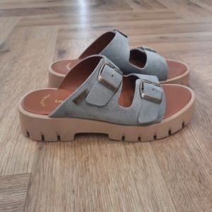 Mules Femme Les tropeziennes-Mules femme en cuir suède-Dès 1982, inspiré par ses nombreux voyages et les traditions amérindiennes, Mo lance ses premiers modèles à succès : des boots à franges et des mocassins bohèmes. Ces créations, véritables invitations au voyage séduisent immédiatement les artistes, les modeuses, les rêveuses et les globe trotteurs en quête de dolce vita. 2005 : La spartiate 30 ans plus tard, animé par le désir de faire rayonner le style tropézien au-delà de ses frontières, Mo revisite la spartiate. Autrefois prisée des cercles les plus exclusifs, cette sandale traditionnelle est sublimée par des détails élégants et contemporains : cuir finement sélectionné, logo et boucles dorées évoquant la lumière de la Côte d’Azur… Sous son regard visionnaire, ces sandales deviennent un symbole d’élégance, une pièce incontournable pour celles qui rêvent d’emporter un fragment de Saint-Tropez à leurs pieds.