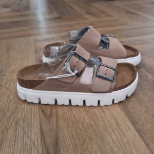 Arizona PAP Chunky Grand classique BIRKENSTOCK, l’Arizona PAP Chunky comble hommes et femmes depuis des décennies. En effet, Papillio pare ici la sandale à double brides d'une semelle compensée tendance aux lignes très profilées. D'abord, le bout biseauté assure un confort maximal durant la marche. Puis, sa tige est confectionnée dans un cuir velours particulièrement doux qui drape le pied comme une seconde peau. PAPILLIO BY BIRKENSTOCK : DES CHAUSSURES À TALON CONFORTABLES Faites la connaissance de notre gamme Papillio : la marque des chaussures à talon et des sandales à plateforme de BIRKENSTOCK. À porter de jour comme de nuit, mélangeant sans peine confort et sophistication, ces modèles vous feront même gagner quelques centimètres. Les chaussures à talon ne sont pas particulièrement réputées pour leur confort. Mais BIRKENSTOCK a relevé le défi. Conçu pour soutenir la forme du pied et la voûte plantaire, le lit de pied original de BIRKENSTOCK constitue le cœur de chaque paire de sandales Papillio. De plus, elle est perfectionnée par des experts au cours de plusieurs décennies. Ainsi, sa structure cible les différentes parties du pied de manière isolée pour que chacune d’entre elles soit bien soutenue. La coque profonde et le moulage au niveau du talon, la semelle rehaussée au niveau des arches et la partie frontale spacieuse pour les orteils maintiennent votre pied dans le bon alignement, ce qui favorise une répartition homogène du poids du corps sur l’ensemble du pied et une démarche naturelle. Ainsi, vous restez à l’aise dans vos chaussures pendant des heures durant, où que vous mène votre journée. LES SANDALES PAPILLIO : UN GAGE DE QUALITÉ BIRKENSTOCK accorde une grande importance à la durabilité, à la qualité et au confort de ses chaussures. C’est pourquoi nos modèles Papillio sont confectionnés en utilisant des matériaux haut de gamme et sont produits de manière responsable. Nos sandales Papillio sont fabriquées dans notre usine BIRKENSTOCK au Portugal et certaines des étapes de production sont même réalisées à la main. Notre engagement envers des produits de qualité et confortables est tangible à travers chacune de nos paires de sandales Papillio, et chaque paire est conçue pour durer.
