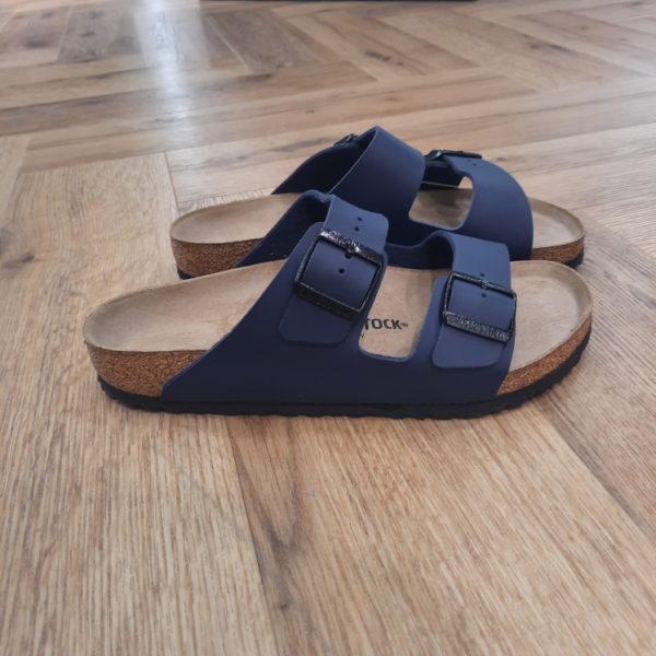 Arizona Navy L'Arizona Navy de BIRKENSTOCK est un grand classique qui séduit les hommes et les femmes depuis des décennies. Cette sobre sandale à deux brides est un parfait exemple de design intemporel. A ce titre, il y a bien longtemps qu’elle s’est imposée comme une chaussure confortable culte. Le dessus est en Birko-Flor®, une matière synthétique hypoallergénique et résistante. BIRKENSTOCK ARIZONA : LE MODÈLE TENDANCE ET CULTE Faites place aux Arizona – les sandales les plus populaires de BIRKENSTOCK. Depuis ses débuts en 1973, le modèle Arizona a conquis les cœurs et fait des millions d’adeptes dans le monde entier. Avec leur design intemporel et confortable, ces sandales sont toujours gage de style. Pour faire honneur à leur popularité, les Arizona ont été déclinées en plus de styles, de couleurs et de matières que n’importe quel autre modèle de BIRKENSTOCK, convenant à chaque occasion et à tous les goûts. Plus que tout autre modèle, les sandales Arizona ont contribué à façonner l’image de BIRKENSTOCK. D’ailleurs, nous parions que lorsque vous pensez à BIRKENSTOCK, ce sont les Arizona qui vous viennent d’emblée à l’esprit. Iconique, ce modèle représente BIRKENSTOCK dans toute son essence. En presque un demi-siècle, le design emblématique a à peine changé en matière de style ou de fonctionnalité. Pourtant, sa popularité n’a pas diminué d’un iota. Une vraie preuve de la renommée et de l’appréciation de ce modèle.