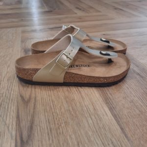 Gizeh Gold Grand classique BIRKENSTOCK, la Gizeh Gold est une chaussure stylée multitalent. Notre élégante sandale à entre-doigts affiche un design minimaliste tendance, tout en offrant un maintien parfait. La présente variante affiche une surface satinée. La tige est confectionnée en Birko-Flor®, un matériau synthétique doux et résistant. Vous les considérez peut-être comme des sandales à papa, et pourtant, les Birkenstocks sont les chaussures les plus branchées (et confortables) du moment. Tous les pieds les adoptent, même ceux des it-girls qui n’hésitent pas à s’afficher avec sandales sur leurs réseaux sociaux. Impossible de ne pas les connaître: les Birkenstocks. Elles sont plus robustes que des tongs, s’accordent avec toutes les tenues et sont d'un confort inégalable. Mais elles sont surtout plus populaires que jamais. GIZEH DE BIRKENSTOCK UNE ODE À LA MODE INTEMPORELLE Découvrez les Gizeh de BIRKENSTOCK : des tongs modernes qui vous permettent de combiner style et fonctionnalité sans effort. Créées en 1983, les Gizeh de BIRKENSTOCK sont entretemps devenues iconiques : elles font partie des modèles les plus populaires et appréciés de BIRKENSTOCK. Grâce à leur esthétique minimaliste et sans chichi, les Gizeh sont une pièce essentielle pour n’importe quelle garde-robe. Elles ont été adoptées par des hommes ou femmes, qui accordent de l’importance à leur look et souhaitent ajouter une touche d’élégance décontractée à leur tenue estivale.