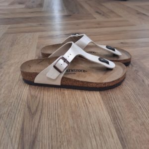 Gizeh Pearl White Grand classique BIRKENSTOCK, la Gizeh Pearl White est une chaussure stylée multitalent. Notre élégante sandale à entre-doigts affiche un design minimaliste tendance, tout en offrant un maintien parfait. La présente variante affiche une surface satinée. La tige est confectionnée en Birko-Flor®, un matériau synthétique doux et résistant. Vous les considérez peut-être comme des sandales à papa, et pourtant, les Birkenstocks sont les chaussures les plus branchées (et confortables) du moment. Tous les pieds les adoptent, même ceux des it-girls qui n’hésitent pas à s’afficher avec sandales sur leurs réseaux sociaux. Impossible de ne pas les connaître: les Birkenstocks. Elles sont plus robustes que des tongs, s’accordent avec toutes les tenues et sont d'un confort inégalable. Mais elles sont surtout plus populaires que jamais. GIZEH DE BIRKENSTOCK UNE ODE À LA MODE INTEMPORELLE Découvrez les Gizeh de BIRKENSTOCK : des tongs modernes qui vous permettent de combiner style et fonctionnalité sans effort. Créées en 1983, les Gizeh de BIRKENSTOCK sont entretemps devenues iconiques : elles font partie des modèles les plus populaires et appréciés de BIRKENSTOCK. Grâce à leur esthétique minimaliste et sans chichi, les Gizeh sont une pièce essentielle pour n’importe quelle garde-robe. Elles ont été adoptées par des hommes ou femmes, qui accordent de l’importance à leur look et souhaitent ajouter une touche d’élégance décontractée à leur tenue estivale.