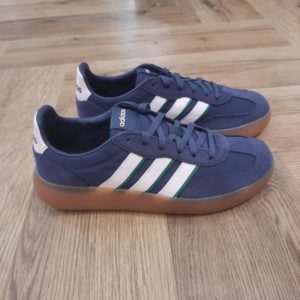 Adidas Barreda Navy: Une sneaker casual inspirée de la culture football. Cette chaussure Adidas Barreda Navy moderne rend hommage au style football vintage. En effet, le suède premium et le nylon s'associent pour créer une tige stylée et résistante. Tout d'abord, sa semelle cupsole en caoutchouc et l'avant-pied en T classique offrent du confort et un style rétro. Que tu arpentes les rues de la ville ou que tu te détendes dans ton café préféré, cette sneaker est faite pour toi. La marque C'est le 18 août 1949 qu'Adi Dassler a démarré l'aventure adidas, avec pour objectif d'améliorer les performances des athlètes. 70 ans plus tard, adidas a laissé sa marque sur le monde du sport, mais aussi celui de la mode, de la musique, de la culture, du développement durable et bien d'autres encore. Voyage avec nous à travers le temps et découvre l'histoire d'adidas avec des modèles qui ont influencé le lifestyle d'aujourd'hui. Juste après la naissance officielle des 3 bandes en 1949, les années 50 ont connu un véritable boom technologique avec des équipements innovants pour les athlètes de classe mondiale. Ainsi, c'est pendant cette décennie qu'est apparue la Samba, toujours portée de nos jours pas les joueurs de Five et de futsal, et toujours présente dans la rue. Pendant les 50's, adidas a développé une chaussure de sprint qui a battu un record du monde et la première chaussure de football conçue avec une semelle en nylon, marquant une vraie nouveauté en termes de confort et de sensations. D'autres modèles ont vu le jour durant cette période, comme la chaussure de basketball Allround, devenue une véritable icône dans les 80's. Ces années ont été révolutionnaires, créant un véritable avant et après pour les sportifs de haut niveau. Mais ce n'était que le début de l'histoire d'adidas.