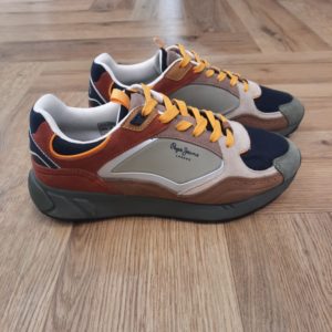 Pepe Jeans Marlon Sports Les baskets Pepe Jeans Marlon Sports sont des baskets pour homme. Celles ci allient parfaitement un design contemporain à un confort maximal. Idéales pour le quotidien, ces baskets présentent un mélange attrayant de matériaux. De plus, elles possèdent des détails en daim sur la pointe, les côtés et le talon qui ajoutent une touche de sophistication. Puis, le tissu en maille sur le dessus assure une respirabilité optimale, gardant vos pieds frais et confortables. Conçues pour un ajustement parfait, elles disposent d'une fermeture à lacets. Puis, elles possèdent des œillets métalliques personnalisés avec le logo "PJL" qui est un clin d'œil à l'authenticité de la marque. Le logo Pepe Jeans thermoscellé sur les côtés et le logo "1973" imprimé sur le talon renforcent leur identité. Pour une foulée douce et amortie, elles intègrent une semelle intérieure thermoformée et amovible ainsi qu'une semelle intermédiaire en phylon de grand volume. La semelle en caoutchouc contrastée de couleurs offre non seulement une excellente traction, mais ajoute également une touche de style urbain à votre look. Fabriquées avec 60 % de cuir de vache, 35 % de polyamide et 5 % de polyuréthane, et une semelle 100 % en caoutchouc. Pour conclure, ces baskets sont le choix parfait pour un style décontracté et à la mode. Histoire de la marque La marque Pepe Jeans London est née à Londres en 1973, sur la mythique avenue de Portobello. Aujourd’hui encore, 50 ans plus tard, elle reste fidèle à son engagement de créer la marque de denim la plus tendance au monde. La personnalité de Pepe Jeans se définit par la diversité culturelle et le caractère cosmopolite de la ville de Londres, lesquels n’ont de cesse d’inspirer les collections femme, homme et junior. La musique, la culture, la mode, Londres, le denim : autant de sources d’inspiration qui font la force de Pepe Jeans.
