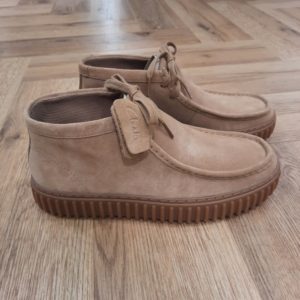Clarks Torhill Hi Sable L’audacieuse semelle extérieure côtelée qui caractérise notre bottine Clarks Torhill Hi Sable est issue de nos archives. Mais elle est tout aussi contemporaine aujourd’hui que dans notre modèle Big Gripper (chaussures à crampons) des années 90. Avec un design à lacets épuré dont les courbes et les contours s’inspirent de notre emblématique Wallabee, elle associe des matériaux de qualité supérieure à des surpiqûres raffinées pour créer la chaussure décontractée ultime inspirée de notre histoire. Nos fondateurs Notre histoire a commencé en 1825 à Street, dans le Somerset, lorsque Cyrus Clark a ouvert une tannerie de cuir, son frère James travaillant à ses côtés. Parmi les tapis en peau de mouton, James a eu un éclair d'inspiration : utiliser les chutes pour créer des pantoufles - minimiser les déchets, maximiser l'ingéniosité et définir les 200 prochaines années de la fabrication de chaussures. Chaque chaussure Clarks, depuis notre toute première paire, utilise cette combinaison distinctive d'innovation et de savoir-faire, soutenant tout ce que nous faisons. Depuis 200 ans, nous avons défini la norme - et ce n'est que le début. En 2025, nous rendons hommage au passé et au présent et célébrons fièrement cet héritage de deux siècles d'innovation et d'impact à travers un tout nouveau film, un livre, une exposition de musée et des collaborations de style.