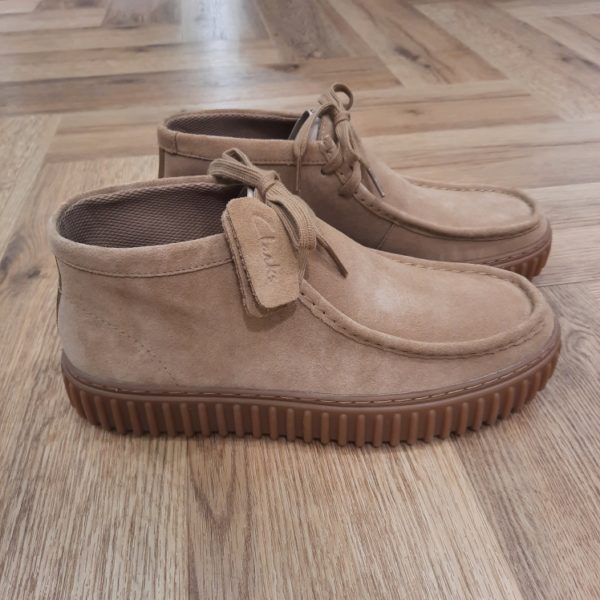 Clarks Torhill Hi Sable L’audacieuse semelle extérieure côtelée qui caractérise notre bottine Clarks Torhill Hi Sable est issue de nos archives. Mais elle est tout aussi contemporaine aujourd’hui que dans notre modèle Big Gripper (chaussures à crampons) des années 90. Avec un design à lacets épuré dont les courbes et les contours s’inspirent de notre emblématique Wallabee, elle associe des matériaux de qualité supérieure à des surpiqûres raffinées pour créer la chaussure décontractée ultime inspirée de notre histoire. Nos fondateurs Notre histoire a commencé en 1825 à Street, dans le Somerset, lorsque Cyrus Clark a ouvert une tannerie de cuir, son frère James travaillant à ses côtés. Parmi les tapis en peau de mouton, James a eu un éclair d'inspiration : utiliser les chutes pour créer des pantoufles - minimiser les déchets, maximiser l'ingéniosité et définir les 200 prochaines années de la fabrication de chaussures. Chaque chaussure Clarks, depuis notre toute première paire, utilise cette combinaison distinctive d'innovation et de savoir-faire, soutenant tout ce que nous faisons. Depuis 200 ans, nous avons défini la norme - et ce n'est que le début. En 2025, nous rendons hommage au passé et au présent et célébrons fièrement cet héritage de deux siècles d'innovation et d'impact à travers un tout nouveau film, un livre, une exposition de musée et des collaborations de style.