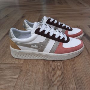 Gola Grandslam Quadrant Découvrez les Gola Grandslam Quadrant, des baskets qui allient élégance et confort. Conçues pour les femmes modernes, ces chaussures se distinguent par leur look chic et décontracté, parfait pour les saisons automne-hiver. La combinaison de teintes blanches et dorées apporte une touche de sophistication, tandis que leur légèreté garantit un confort optimal tout au long de la journée. Que ce soit pour une sortie entre amis ou une séance de shopping, ces baskets seront votre allié idéal. La marque Gola est une marque principalement connue pour ses chaussures de sport. Elle a été créé en 1905 à Leicester, au Royaume Uni. Pour l'anecdote, personne ne sait exactement d'où vient le nom de la marque. Pourtant, une légende urbaine raconte qu'elle doit son nom à l'anagramme du mot "Goal" (qui signifie "but" en anglais). La marque commence à être connue à la fin des années 1960. Notamment dans le sport notamment avec la Harrier qui reste aujourd'hui encore le modèle phare de la marque anglaise. En effet, elle a très vite été adoptée par le grand public. Fort de son histoire, la marque a su traverser les générations et est aujourd'hui une marque streetwear à part entière qui sait innover et suivre les tendances. On a d'ailleurs pu voir une collection 100 % vegan sortir des tuyaux en 2019, preuve de la capacité de Gola à s'adapter au marché actuel !