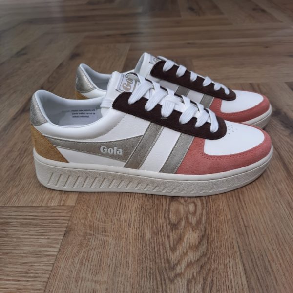 Gola Grandslam Quadrant Découvrez les Gola Grandslam Quadrant, des baskets qui allient élégance et confort. Conçues pour les femmes modernes, ces chaussures se distinguent par leur look chic et décontracté, parfait pour les saisons automne-hiver. La combinaison de teintes blanches et dorées apporte une touche de sophistication, tandis que leur légèreté garantit un confort optimal tout au long de la journée. Que ce soit pour une sortie entre amis ou une séance de shopping, ces baskets seront votre allié idéal. La marque Gola est une marque principalement connue pour ses chaussures de sport. Elle a été créé en 1905 à Leicester, au Royaume Uni. Pour l'anecdote, personne ne sait exactement d'où vient le nom de la marque. Pourtant, une légende urbaine raconte qu'elle doit son nom à l'anagramme du mot "Goal" (qui signifie "but" en anglais). La marque commence à être connue à la fin des années 1960. Notamment dans le sport notamment avec la Harrier qui reste aujourd'hui encore le modèle phare de la marque anglaise. En effet, elle a très vite été adoptée par le grand public. Fort de son histoire, la marque a su traverser les générations et est aujourd'hui une marque streetwear à part entière qui sait innover et suivre les tendances. On a d'ailleurs pu voir une collection 100 % vegan sortir des tuyaux en 2019, preuve de la capacité de Gola à s'adapter au marché actuel !