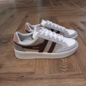 Gola Superslam Blaze Découvrez les Gola Superslam Blaze, une fusion parfaite de style et de confort pour les femmes modernes. Avec leur design élégant, ces baskets affichent une palette de couleurs gris et doré, qui ajoute une touche de sophistication à toutes vos tenues. Conçues pour le quotidien, elles sont réalisées en cuir et en synthétique de haute qualité, garantissant une durabilité exceptionnelle tout en étant respectueuses de l'environnement grâce à l'utilisation de matières recyclées. Légeres et agréables à porter, ces chaussures deviendront rapidement vos incontournables de l'automne et de l'hiver. La marque Gola est une marque principalement connue pour ses chaussures de sport. Elle a été créé en 1905 à Leicester, au Royaume Uni. Pour l'anecdote, personne ne sait exactement d'où vient le nom de la marque. Pourtant, une légende urbaine raconte qu'elle doit son nom à l'anagramme du mot "Goal" (qui signifie "but" en anglais). La marque commence à être connue à la fin des années 1960. Notamment dans le sport notamment avec la Harrier qui reste aujourd'hui encore le modèle phare de la marque anglaise. En effet, elle a très vite été adoptée par le grand public. Fort de son histoire, la marque a su traverser les générations et est aujourd'hui une marque streetwear à part entière qui sait innover et suivre les tendances. On a d'ailleurs pu voir une collection 100 % vegan sortir des tuyaux en 2019, preuve de la capacité de Gola à s'adapter au marché actuel !