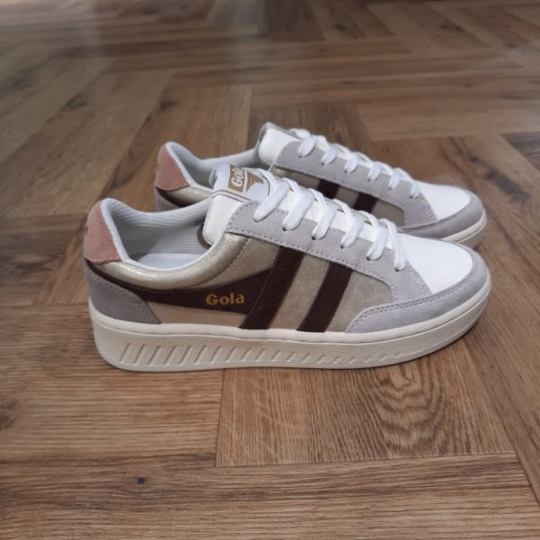Gola Superslam Blaze Découvrez les Gola Superslam Blaze, une fusion parfaite de style et de confort pour les femmes modernes. Avec leur design élégant, ces baskets affichent une palette de couleurs gris et doré, qui ajoute une touche de sophistication à toutes vos tenues. Conçues pour le quotidien, elles sont réalisées en cuir et en synthétique de haute qualité, garantissant une durabilité exceptionnelle tout en étant respectueuses de l'environnement grâce à l'utilisation de matières recyclées. Légeres et agréables à porter, ces chaussures deviendront rapidement vos incontournables de l'automne et de l'hiver. La marque Gola est une marque principalement connue pour ses chaussures de sport. Elle a été créé en 1905 à Leicester, au Royaume Uni. Pour l'anecdote, personne ne sait exactement d'où vient le nom de la marque. Pourtant, une légende urbaine raconte qu'elle doit son nom à l'anagramme du mot "Goal" (qui signifie "but" en anglais). La marque commence à être connue à la fin des années 1960. Notamment dans le sport notamment avec la Harrier qui reste aujourd'hui encore le modèle phare de la marque anglaise. En effet, elle a très vite été adoptée par le grand public. Fort de son histoire, la marque a su traverser les générations et est aujourd'hui une marque streetwear à part entière qui sait innover et suivre les tendances. On a d'ailleurs pu voir une collection 100 % vegan sortir des tuyaux en 2019, preuve de la capacité de Gola à s'adapter au marché actuel !