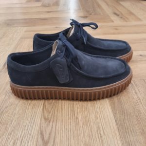 Clarks Torhill Lo Navy L’audacieuse semelle extérieure côtelée qui caractérise la Clarks Torhill Lo Navy est issue de nos archives, mais elle est tout aussi contemporaine aujourd’hui que dans notre modèle Big Gripper (chaussures à crampons) des années 90. Avec un design à lacets épuré dont les courbes et les contours s’inspirent de notre emblématique Wallabee, elle associe des matériaux de qualité supérieure à des surpiqûres raffinées pour créer la chaussure décontractée ultime inspirée de notre histoire. Nos fondateurs Notre histoire a commencé en 1825 à Street, dans le Somerset, lorsque Cyrus Clark a ouvert une tannerie de cuir, son frère James travaillant à ses côtés. Parmi les tapis en peau de mouton, James a eu un éclair d'inspiration : utiliser les chutes pour créer des pantoufles - minimiser les déchets, maximiser l'ingéniosité et définir les 200 prochaines années de la fabrication de chaussures. Chaque chaussure Clarks, depuis notre toute première paire, utilise cette combinaison distinctive d'innovation et de savoir-faire, soutenant tout ce que nous faisons. Depuis 200 ans, nous avons défini la norme - et ce n'est que le début. En 2025, nous rendons hommage au passé et au présent et célébrons fièrement cet héritage de deux siècles d'innovation et d'impact à travers un tout nouveau film, un livre, une exposition de musée et des collaborations de style.