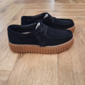 Clarks Torhill Bee Black L’audacieuse semelle extérieure côtelée qui caractérise la Clarks Torhill Bee Black est issue de nos archives, mais elle est tout aussi contemporaine aujourd’hui que dans notre modèle Big Gripper (chaussures à crampons) des années 90. Avec un design à lacets épuré dont les courbes et les contours s’inspirent de notre emblématique Wallabee, elle associe des matériaux de qualité supérieure à des surpiqûres raffinées pour créer la chaussure décontractée ultime inspirée de notre histoire. Nos fondateurs Notre histoire a commencé en 1825 à Street, dans le Somerset, lorsque Cyrus Clark a ouvert une tannerie de cuir, son frère James travaillant à ses côtés. Parmi les tapis en peau de mouton, James a eu un éclair d'inspiration : utiliser les chutes pour créer des pantoufles - minimiser les déchets, maximiser l'ingéniosité et définir les 200 prochaines années de la fabrication de chaussures. Chaque chaussure Clarks, depuis notre toute première paire, utilise cette combinaison distinctive d'innovation et de savoir-faire, soutenant tout ce que nous faisons. Depuis 200 ans, nous avons défini la norme - et ce n'est que le début. En 2025, nous rendons hommage au passé et au présent et célébrons fièrement cet héritage de deux siècles d'innovation et d'impact à travers un tout nouveau film, un livre, une exposition de musée et des collaborations de style.