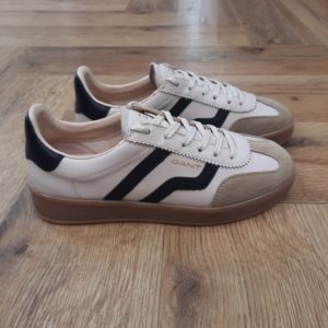 Gant Cuzima Beige La chaussure Gant Cuzima Beige est une paire de baskets d'inspiration rétro, qui se porte en toute saison. Tout d'abord, elles sont dotées d'une tige en cuir de qualité supérieure. De plus, elles arborent des finitions de couleur contrastante au niveau du bout, du talon et sur le côté. Puis, sa fine semelle extérieure en caoutchouc et la doublure en coton éponge apportent un style vintage à l'ensemble. Les baskets Gant Cuzima pour femme sont la fusion parfaite entre style rétro et confort. Avec leur design intemporel et leurs matériaux de qualité supérieure, elles sont idéales pour toute occasion, garantissant un look décontracté et moderne qui ne passera pas inaperçu. La marque Quand Bernard Gant, un immigrant ukrainien, arrive à New-York en 1914, il se plonge directement au cœur des métiers du prêt-à-porter en travaillant dans un atelier de confection de chemises dans le centre de la ville. Ce n'est que quelques années plus tard, alors qu'il a déménagé à New Haven dans le Connecticut qu'il lancera l'entreprise familiale à l'aide de sa femme, également dans le métier. Rapidement, il fabrique des chemises pour les plus grandes marques du pays tel que Brooks Brothers. Si le style de Gant a beaucoup évolué au cours des années, il ne s'est jamais vraiment détaché de son image de marque Américaine traditionnelle adepte du style Ivy avec comme produit phare la chemise à col boutonné. Après avoir été suédoise, la marque a été rachetée en 2008 par le groupe suisse Maus Frères, qui détient entre autres Lacoste et Aigle, mais elle garde encore ses valeurs originelles : celles de Bernard Gant.