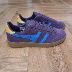 Gola Viper Purple Avec ses racines remontant au design Gola de 1976, la Gola Viper Violet associe une tige courte et élégante à bout en T et une semelle à sept œillets. Cette association donne naissance à une basket classique aux proportions parfaites. En effet, celle ci est agrémentée d'une semelle en gomme tendance. On adore les lignes minimalistes de cette basket femme en daim moelleux, présentée ici en prune avec une bordure Wingflash Gola bleu Pacifique et un talon jaune pollen. La Viper nous transporte à l'âge d'or de Gola. La marque Gola est une marque principalement connue pour ses chaussures de sport. Elle a été créé en 1905 à Leicester, au Royaume Uni. Pour l'anecdote, personne ne sait exactement d'où vient le nom de la marque. Pourtant, une légende urbaine raconte qu'elle doit son nom à l'anagramme du mot "Goal" (qui signifie "but" en anglais). La marque commence à être connue à la fin des années 1960. Notamment dans le sport notamment avec la Harrier qui reste aujourd'hui encore le modèle phare de la marque anglaise. En effet, elle a très vite été adoptée par le grand public. Fort de son histoire, la marque a su traverser les générations et est aujourd'hui une marque streetwear à part entière qui sait innover et suivre les tendances. On a d'ailleurs pu voir une collection 100 % vegan sortir des tuyaux en 2019, preuve de la capacité de Gola à s'adapter au marché actuel !