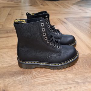 1460 Pascal Bex Pour célébrer les 60 ans de Dr. Martens, nous avons repris notre silhouette originale et l'avons reconstruite sur une semelle Bex empilée cousue Goodyear. Fabriquée à partir de cuir de Pise souple, notre 1460 Pascal Bex est une variante d'un classique, mais est immédiatement reconnaissable comme une botte Docs. Fini avec des coutures passepoilées jaunes, des œillets marqués AirWair et une boucle de talon noire et jaune. The History of Dr. Martens Dr. Martens s'attache aux personnes qui ont leur propre style mais qui partagent un même esprit, des personnes authentiques qui représentent quelque chose de concret. Qui aiment s'exprimer honnêtement. Qui sont différentes. Sur un plan stylistique, les silhouettes épurées de Dr. Martens permettent à celles et ceux qui les portent de les intégrer à leur style individuel et unique. Sur un plan pratique, la solidité et le confort réputés de nos chaussures les rendent parfaites pour un quotidien partagé entre concert et mode urbaine. Et finalement, sur un plan émotionnel, elles sont une marque d'attitude et de confiance en soi. Mais ça n'a pas toujours été le cas. À l'origine, Dr. Martens proposait des boots de travail simples qui ont même brièvement été vendues comme des chaussures de jardinage. Donc comment est-ce que ces boots utilitaires sont devenues l'une des icônes culturelles les plus importantes de notre époque moderne ? C'est une histoire unique et intéressante...