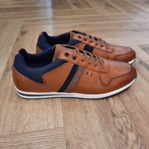Redskins Living Cognac Avec cette sneaker, Redskins apporte la preuve irréfutable que le sportswear a encore de beaux jours devant lui ! On lui donne un bon point pour sa ligne dynamique appuyée par une tige en cuir et textile et un vrai coloris marron. Sa doublure en cuir et textile s'allie à une semelle en caoutchouc. Mais plus que d'en parler, le mieux est encore de l'essayer ! Fabriquées au Portugal. L'histoire de la marque Lorsque l’on parle de la célèbre marque de cuir Redskins, on pense immédiatement au look américain, au style biker avec ce petit côté rock’n roll qui souligne la tenue masculine. Or c’est bel et bien en France qu’est née la marque, créée par Serge ABOUJEDID. C’est donc en 1984 que la marque Redskins voit le jour, inspirée de la culture américaine et de la tendance rock’n roll, empreint d’une touche contemporaine dans chaque création de la marque. Cette marque résolument française est née à Gennevilliers et oriente ses collections vers la fabrication de blousons et vestes en cuir pour homme. A partir des année 90, la marque a mis au gout du jour le modèle teddy Redskins, qui n’a de cesse d’être la pièce indémodable de votre garde-robe. Aujourd’hui, stylistes et créateurs ont choisi de diversifier leur gamme pour proposer des chaussures en cuir Redskins, la maroquinerie et divers accessoires à la vente. Une stratégie payante puisque la marque devient aujourd’hui la référence du cuir de qualité. Toujours enclin à suivre le mouvement culturel et notamment cinématographique, Redskins n’hésite pas à s’associer à des personnalités influentes pour proposer ses créations au grand public. Shemar Moore, David Duchovny ou encore Johnny Hallyday ont fait partie de leur figure pour représenter leur collection.