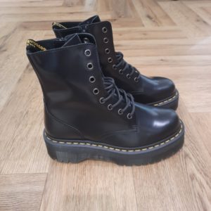 Jadon Polished Smooth Les boots Jadon Polished Smooth repensent six décennies d'attitude Dr. Martens en une paire plateforme spectaculaire. En effet, elles sont inspirées de nos boots Original à 8 œillets. D'abord, les boots Jadon sont fabriquées en cuir Polished Smooth que vous pouvez cirer ou laisser tel quel. De plus, l'impressionnante semelle Quad est soulignée de nos rainures et de nos surpiqûres jaunes signature. Puis, le talon se pare de notre boucle d'enfilage jaune et noire. La fermeture zippée intérieure permet de les enfiler et retirer facilement. L'histoire Dr Martens En 1945, Klaus Maertens, un médecin allemand, crée ces chaussures à la suite d’un accident de ski. Des chaussures avec une semelle soudée. C’est une soudure à chaud qui permet d’emprisonner l’air, et c’est ce qui fait qu’elle sera très confortable et va devenir au début, une chaussure orthopédique. Pour fabriquer la semelle, Klaus Maertens récupère le caoutchouc des avions militaires abandonnés dans les hangars, le métal des vestes des soldats pour faire les œillets de la botte, et le cuir sur certains de leurs pantalons. Le succès est immédiat en 1947. Grâce à ces chaussures, les gens peuvent marcher dans des rues souvent détruites par la guerre. La compagnie ouvre une usine à Munich en 1952 et crée déjà 200 styles différents de chaussures. Cette invention allemande est adoptée en Angleterre lorsque Bill Griggs remarque ce modèle de chaussure, achète la licence et l’améliore. Il bombe l’avant et va faire cette fameuse semelle à rainures qui est transparente, qui permet de voir un peu où se cache l’air dans la chaussure. Aussi, d’avoir cette fameuse couture jaune permet de la reconnaître immédiatement de très loin. Les ouvriers, les policiers, les postiers, le personnel des hôpitaux et les cols bleus se mettent à porter des Dr. Martens. Plus tard, les skinheads ainsi que des groupes radicaux et racistes les portent pour afficher leur révolte contre la société.