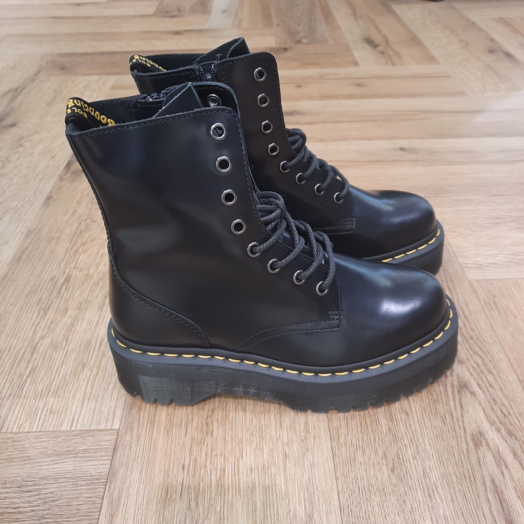 Jadon Polished Smooth Les boots Jadon Polished Smooth repensent six décennies d'attitude Dr. Martens en une paire plateforme spectaculaire. En effet, elles sont inspirées de nos boots Original à 8 œillets. D'abord, les boots Jadon sont fabriquées en cuir Polished Smooth que vous pouvez cirer ou laisser tel quel. De plus, l'impressionnante semelle Quad est soulignée de nos rainures et de nos surpiqûres jaunes signature. Puis, le talon se pare de notre boucle d'enfilage jaune et noire. La fermeture zippée intérieure permet de les enfiler et retirer facilement. L'histoire Dr Martens En 1945, Klaus Maertens, un médecin allemand, crée ces chaussures à la suite d’un accident de ski. Des chaussures avec une semelle soudée. C’est une soudure à chaud qui permet d’emprisonner l’air, et c’est ce qui fait qu’elle sera très confortable et va devenir au début, une chaussure orthopédique. Pour fabriquer la semelle, Klaus Maertens récupère le caoutchouc des avions militaires abandonnés dans les hangars, le métal des vestes des soldats pour faire les œillets de la botte, et le cuir sur certains de leurs pantalons. Le succès est immédiat en 1947. Grâce à ces chaussures, les gens peuvent marcher dans des rues souvent détruites par la guerre. La compagnie ouvre une usine à Munich en 1952 et crée déjà 200 styles différents de chaussures. Cette invention allemande est adoptée en Angleterre lorsque Bill Griggs remarque ce modèle de chaussure, achète la licence et l’améliore. Il bombe l’avant et va faire cette fameuse semelle à rainures qui est transparente, qui permet de voir un peu où se cache l’air dans la chaussure. Aussi, d’avoir cette fameuse couture jaune permet de la reconnaître immédiatement de très loin. Les ouvriers, les policiers, les postiers, le personnel des hôpitaux et les cols bleus se mettent à porter des Dr. Martens. Plus tard, les skinheads ainsi que des groupes radicaux et racistes les portent pour afficher leur révolte contre la société.