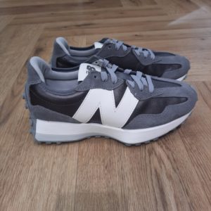 New Balance 327GLB--Baskets basses WS327GLB en nubuck-327 Noir / Argent- 1906 La marque New Balance a été créée par le cordonnier orthopédiste William R. Riley. Alors qu’il observait des poules dans son jardin et constatait qu’elles avaient une position extrêmement stable avec leurs trois griffes, il eut l‘idée de développer une nouvelle semelle intérieure à trois appuis. Pour lui, c’était la «nouvelle balance». Et en même temps, il avait trouvé le nom adéquat pour son entreprise.