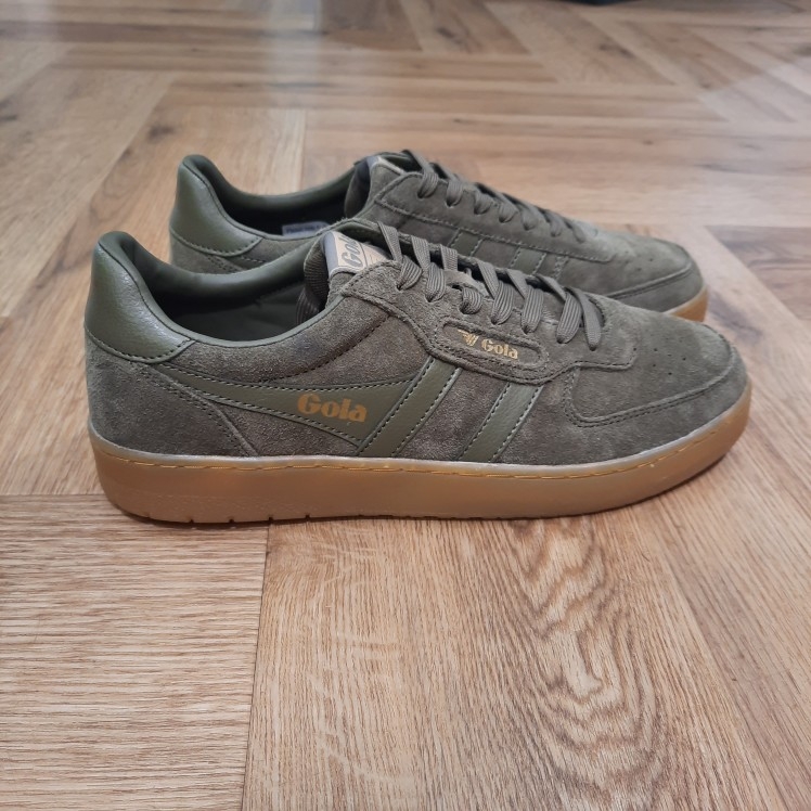 Gola Hawk Kaki La toute nouvelle Gola Hawk Kaki rejoint la gamme emblématique. En effet, le modèle authentique Hawk est revisité avec une tige en daim de qualité couleur tabac et une semelle en gomme. Tout d'abord, son style chaleureux et décontracté dégage une touche vintage. En effet, c'est le complément idéal de toute garde-robe, pour un usage quotidien et pour donner du caractère à toutes vos tenues. La marque Gola est une marque principalement connue pour ses chaussures de sport. Elle a été créé en 1905 à Leicester, au Royaume Uni. Pour l'anecdote, personne ne sait exactement d'où vient le nom de la marque. Pourtant, une légende urbaine raconte qu'elle doit son nom à l'anagramme du mot "Goal" (qui signifie "but" en anglais). La marque commence à être connue à la fin des années 1960. Notamment dans le sport notamment avec la Harrier qui reste aujourd'hui encore le modèle phare de la marque anglaise. En effet, elle a très vite été adoptée par le grand public. Fort de son histoire, la marque a su traverser les générations et est aujourd'hui une marque streetwear à part entière qui sait innover et suivre les tendances. On a d'ailleurs pu voir une collection 100 % vegan sortir des tuyaux en 2019, preuve de la capacité de Gola à s'adapter au marché actuel !