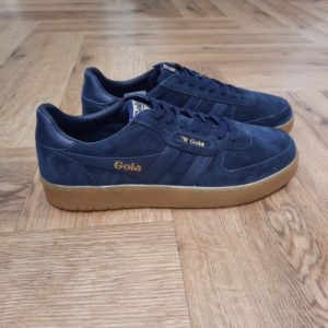 Gola Hawk Navy La toute nouvelle Gola Hawk Navy rejoint la gamme emblématique. En effet, le modèle authentique Hawk est revisité avec une tige en daim de qualité couleur tabac et une semelle en gomme. Tout d'abord, son style chaleureux et décontracté dégage une touche vintage. En effet, c'est le complément idéal de toute garde-robe, pour un usage quotidien et pour donner du caractère à toutes vos tenues. La marque Gola est une marque principalement connue pour ses chaussures de sport. Elle a été créé en 1905 à Leicester, au Royaume Uni. Pour l'anecdote, personne ne sait exactement d'où vient le nom de la marque. Pourtant, une légende urbaine raconte qu'elle doit son nom à l'anagramme du mot "Goal" (qui signifie "but" en anglais). La marque commence à être connue à la fin des années 1960. Notamment dans le sport notamment avec la Harrier qui reste aujourd'hui encore le modèle phare de la marque anglaise. En effet, elle a très vite été adoptée par le grand public. Fort de son histoire, la marque a su traverser les générations et est aujourd'hui une marque streetwear à part entière qui sait innover et suivre les tendances. On a d'ailleurs pu voir une collection 100 % vegan sortir des tuyaux en 2019, preuve de la capacité de Gola à s'adapter au marché actuel !