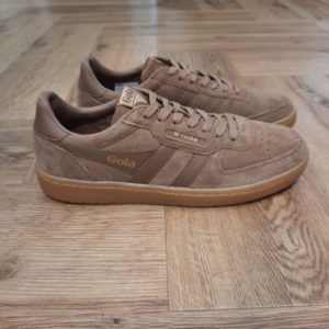 Gola Hawk Tabac La toute nouvelle Gola Hawk Tabac rejoint la gamme emblématique. En effet, le modèle authentique Hawk est revisité avec une tige en daim de qualité couleur tabac et une semelle en gomme. Tout d'abord, son style chaleureux et décontracté dégage une touche vintage. En effet, c'est le complément idéal de toute garde-robe, pour un usage quotidien et pour donner du caractère à toutes vos tenues. La marque Gola est une marque principalement connue pour ses chaussures de sport. Elle a été créé en 1905 à Leicester, au Royaume Uni. Pour l'anecdote, personne ne sait exactement d'où vient le nom de la marque. Pourtant, une légende urbaine raconte qu'elle doit son nom à l'anagramme du mot "Goal" (qui signifie "but" en anglais). La marque commence à être connue à la fin des années 1960. Notamment dans le sport notamment avec la Harrier qui reste aujourd'hui encore le modèle phare de la marque anglaise. En effet, elle a très vite été adoptée par le grand public. Fort de son histoire, la marque a su traverser les générations et est aujourd'hui une marque streetwear à part entière qui sait innover et suivre les tendances. On a d'ailleurs pu voir une collection 100 % vegan sortir des tuyaux en 2019, preuve de la capacité de Gola à s'adapter au marché actuel !