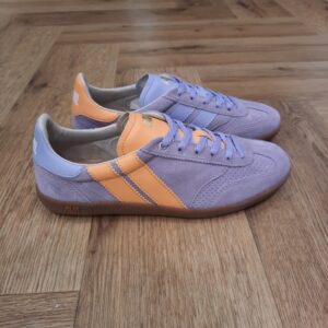 Pulse Lilac Sunrise Les Pulse Lilac Sunrise sont des sneakers asymétriques de la collection Caval qui fusionnent un look sportswear à l'élégance des paires de handball des années 90. Chaque détail, du bout golf, à la plaque perforée, en passant par les découpes croquet, le cousu Strobel, le lacet tricot et les semelles en gomme affûtées, évoque un style rétro-preppy sophistiqué. Souples et flexibles, elles promettent confort et allure pour toutes vos tenues. Avec 7 différences uniques à découvrir, les Pulse ne sont pas de simples sneakers, c'est un bond en avant pour votre style au quotidien. L’histoire de CAVAL Tout d'abord, CAVAL c’est une histoire d’amitié. Trois amis d’école de commerce : Achille, Benoît et Simon. En effet, Simon et Achille se sont rapprochés lorsqu’ils ont découvert qu’ils portaient des chaussures dépareillées depuis leur enfance ! Benoit, un bon ami d’Achille avec une fibre artistique, a été séduit par l’idée de créer des baskets élégamment dépareillées. Il est donc venu compléter l’équipe. Les baskets jouent sur l’asymétrie à travers un jeu des 7 différences qui créé un dialogue entre les deux pieds. Au-delà du dépareillement, les baskets CAVAL sont mixtes, haut de gamme et made in Europe. Ou plus simplement : des baskets Hors Paires. Elles sont fabriquées au Portugal, berceau du savoir-faire de la chaussure en cuir, avec du cuir italien pleine fleur. Côté conception, elles sont imaginées et dessinées en France. Les valeurs Chez CAVAL, la devise est de faire les choses sérieusement sans se prendre au sérieux. Il y a le goût des choses bien faites avec un haut niveau de qualité. Et d’un autre côté, l’envie de prendre le monde au second degré, avec recul. Cela s’exprime dans leur communication décalée et qui joue sur l’actualité ou l’absurde. CAVAL vient de l’expression « être en cavale » que les fondateurs interprètent comme une fuite des codes, des automatismes, et bien sûr, de la symétrie ! Pour conclure, être en CAVAL, c’est se sentir libre d’affirmer sa différence avec originalité et élégance.