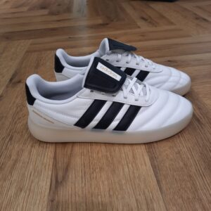 Adidas Barreda Mundial La chaussure Adidas Barreda Mundial incarne l’élégance intemporelle. D'abord, inspirée par l’esthétique classique des crampons de football vintage, elle marie avec fluidité héritage et innovation moderne. Puis, conçue en suède et cuir premium, elle allie style unique et fonctionnalité. De plus, sa construction moderne en semelle Cupsole offre confort et allure contemporaine, parfaite pour les amateurs de streetwear. Le logo adidas, avec les 3 bandes sur le côté et le logo linéaire sur la languette, affirme fièrement son héritage adidas. Enfin, que ce soit pour arpenter les rues de la ville ou profiter de sorties décontractées, cette chaussure est le choix idéal pour allier style et performance. La marque C'est le 18 août 1949 qu'Adi Dassler a démarré l'aventure adidas, avec pour objectif d'améliorer les performances des athlètes. 70 ans plus tard, adidas a laissé sa marque sur le monde du sport, mais aussi celui de la mode, de la musique, de la culture, du développement durable et bien d'autres encore. Voyage avec nous à travers le temps et découvre l'histoire d'adidas avec des modèles qui ont influencé le lifestyle d'aujourd'hui. Juste après la naissance officielle des 3 bandes en 1949, les années 50 ont connu un véritable boom technologique avec des équipements innovants pour les athlètes de classe mondiale. Ainsi, c'est pendant cette décennie qu'est apparue la Samba, toujours portée de nos jours pas les joueurs de Five et de futsal, et toujours présente dans la rue. Pendant les 50's, adidas a développé une chaussure de sprint qui a battu un record du monde et la première chaussure de football conçue avec une semelle en nylon, marquant une vraie nouveauté en termes de confort et de sensations. D'autres modèles ont vu le jour durant cette période, comme la chaussure de basketball Allround, devenue une véritable icône dans les 80's. Ces années ont été révolutionnaires, créant un véritable avant et après pour les sportifs de haut niveau. Mais ce n'était que le début de l'histoire d'adidas