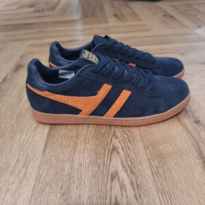 Gola Equipe Navy Orange Les baskets Gola Equipe Navy Orange sont un choix idéal pour ceux qui recherchent à allier style et confort au quotidien. Conçues par la marque britannique renommée Gola, ces sneakers incarnent l'élégance décontractée tout en offrant des performances exceptionnelles. Fabriquées avec un soin particulier, ces baskets sont en suède de haute qualité, ce qui leur confère une texture douce et agréable au toucher. Le suède n'est pas seulement esthétique, il contribue également à la durabilité de la chaussure, résistant aux épreuves du temps et aux aléas du quotidien. Le design des Baskets Gola Equipe II Suede est influencé par le style rétro, inspiré des classiques du sport, tout en intégrant des éléments contemporains qui plairont à tous les amateurs de mode. Leur silouhette classique les rend facilement portables avec une variété de tenues, que ce soit pour un look décontracté ou une sortie plus soignée. Parfaites pour les sorties décontractées, les promenades en ville, ou même pour rehausser vos tenues de bureau, les Baskets Gola Equipe II Suede répondent à toutes vos attentes. Adoptez ces sneakers pour un look tendance et confortable, qui vous accompagnera en toute saison, tout en ajoutant une touche de sophistication à votre style quotidien. Avec la réputation de Gola pour sa qualité et son style intemporel, chaque paire de Baskets Equipe II Suede est un investissement judicieux pour votre garde-robe. Elles renforcent non seulement votre look, mais vous permettent également d'exprimer votre personnalité et votre sens du style.