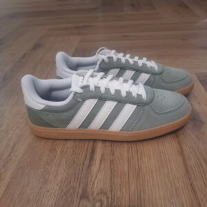 Adidas Breaknet Kaki: Une sneaker stylée et respirante qui revisite un classique. Ta sneaker classique Adidas Breaknet Kaki passe au niveau supérieur. Élégante et stylée, cette version t'accompagne de ta promenade matinale à ton dîner en ville. Des détails perforés gardent les pieds au frais. Sa tige souple, montée sur une semelle extérieure en caoutchouc classique, te suit dans tes aventures quotidiennes. Cette sneaker adidas est agrémentée des 3 bandes iconiques sur les côtés. La marque C'est le 18 août 1949 qu'Adi Dassler a démarré l'aventure adidas, avec pour objectif d'améliorer les performances des athlètes. 70 ans plus tard, adidas a laissé sa marque sur le monde du sport, mais aussi celui de la mode, de la musique, de la culture, du développement durable et bien d'autres encore. Voyage avec nous à travers le temps et découvre l'histoire d'adidas avec des modèles qui ont influencé le lifestyle d'aujourd'hui. Juste après la naissance officielle des 3 bandes en 1949, les années 50 ont connu un véritable boom technologique avec des équipements innovants pour les athlètes de classe mondiale. Ainsi, c'est pendant cette décennie qu'est apparue la Samba, toujours portée de nos jours pas les joueurs de Five et de futsal, et toujours présente dans la rue. Pendant les 50's, adidas a développé une chaussure de sprint qui a battu un record du monde et la première chaussure de football conçue avec une semelle en nylon, marquant une vraie nouveauté en termes de confort et de sensations. D'autres modèles ont vu le jour durant cette période, comme la chaussure de basketball Allround, devenue une véritable icône dans les 80's. Ces années ont été révolutionnaires, créant un véritable avant et après pour les sportifs de haut niveau. Mais ce n'était que le début de l'histoire d'adidas.