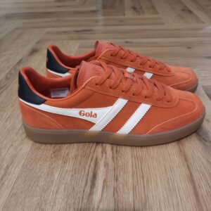 Gola Viper Orange Les baskets Gola Viper Orange sont un incontournable pour tous les amateurs de sneakers et de style rétro. En effet, la marque Gola est connue pour ses designs intemporels et sa qualité supérieure. Celle ci a encore frappé fort avec ce modèle emblématique. Fabriquées avec des matériaux de haute qualité, ces baskets offrent un confort optimal tout en étant résistantes et durables. La combinaison de cuir et de daim donne à ces chaussures un look élégant et vintage, qui s'adapte parfaitement à toutes les tenues. Que ce soit pour une journée décontractée en ville ou pour une soirée entre amis, les Baskets Gola Viper seront votre allié mode idéal. Leur design classique et épuré est rehaussé par les célèbres bandes Gola sur les côtés, qui ajoutent une touche de style unique à ces chaussures. De plus, leur semelle en caoutchouc offre une adhérence optimale, vous permettant de marcher en toute confiance et confort. La marque Gola est une marque principalement connue pour ses chaussures de sport. Elle a été créé en 1905 à Leicester, au Royaume Uni. Pour l'anecdote, personne ne sait exactement d'où vient le nom de la marque. Pourtant, une légende urbaine raconte qu'elle doit son nom à l'anagramme du mot "Goal" (qui signifie "but" en anglais). La marque commence à être connue à la fin des années 1960. Notamment dans le sport notamment avec la Harrier qui reste aujourd'hui encore le modèle phare de la marque anglaise. En effet, elle a très vite été adoptée par le grand public. Fort de son histoire, la marque a su traverser les générations et est aujourd'hui une marque streetwear à part entière qui sait innover et suivre les tendances. On a d'ailleurs pu voir une collection 100 % vegan sortir des tuyaux en 2019, preuve de la capacité de Gola à s'adapter au marché actuel !