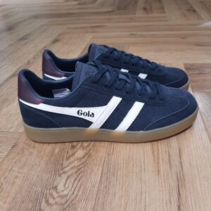 Gola Viper Navy White Les baskets Gola Viper Navy White sont un incontournable pour tous les amateurs de sneakers et de style rétro. En effet, la marque Gola est connue pour ses designs intemporels et sa qualité supérieure. Celle ci a encore frappé fort avec ce modèle emblématique. Fabriquées avec des matériaux de haute qualité, ces baskets offrent un confort optimal tout en étant résistantes et durables. La combinaison de cuir et de daim donne à ces chaussures un look élégant et vintage, qui s'adapte parfaitement à toutes les tenues. Que ce soit pour une journée décontractée en ville ou pour une soirée entre amis, les Baskets Gola Viper seront votre allié mode idéal. Leur design classique et épuré est rehaussé par les célèbres bandes Gola sur les côtés, qui ajoutent une touche de style unique à ces chaussures. De plus, leur semelle en caoutchouc offre une adhérence optimale, vous permettant de marcher en toute confiance et confort. La marque Gola est une marque principalement connue pour ses chaussures de sport. Elle a été créé en 1905 à Leicester, au Royaume Uni. Pour l'anecdote, personne ne sait exactement d'où vient le nom de la marque. Pourtant, une légende urbaine raconte qu'elle doit son nom à l'anagramme du mot "Goal" (qui signifie "but" en anglais). La marque commence à être connue à la fin des années 1960. Notamment dans le sport notamment avec la Harrier qui reste aujourd'hui encore le modèle phare de la marque anglaise. En effet, elle a très vite été adoptée par le grand public. Fort de son histoire, la marque a su traverser les générations et est aujourd'hui une marque streetwear à part entière qui sait innover et suivre les tendances. On a d'ailleurs pu voir une collection 100 % vegan sortir des tuyaux en 2019, preuve de la capacité de Gola à s'adapter au marché actuel !