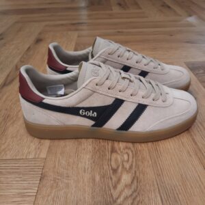 Gola Viper Beige Les baskets Gola Viper Beige sont un incontournable pour tous les amateurs de sneakers et de style rétro. En effet, la marque Gola est connue pour ses designs intemporels et sa qualité supérieure. Celle ci a encore frappé fort avec ce modèle emblématique. Fabriquées avec des matériaux de haute qualité, ces baskets offrent un confort optimal tout en étant résistantes et durables. La combinaison de cuir et de daim donne à ces chaussures un look élégant et vintage, qui s'adapte parfaitement à toutes les tenues. Que ce soit pour une journée décontractée en ville ou pour une soirée entre amis, les Baskets Gola Viper seront votre allié mode idéal. Leur design classique et épuré est rehaussé par les célèbres bandes Gola sur les côtés, qui ajoutent une touche de style unique à ces chaussures. De plus, leur semelle en caoutchouc offre une adhérence optimale, vous permettant de marcher en toute confiance et confort. La marque Gola est une marque principalement connue pour ses chaussures de sport. Elle a été créé en 1905 à Leicester, au Royaume Uni. Pour l'anecdote, personne ne sait exactement d'où vient le nom de la marque. Pourtant, une légende urbaine raconte qu'elle doit son nom à l'anagramme du mot "Goal" (qui signifie "but" en anglais). La marque commence à être connue à la fin des années 1960. Notamment dans le sport notamment avec la Harrier qui reste aujourd'hui encore le modèle phare de la marque anglaise. En effet, elle a très vite été adoptée par le grand public. Fort de son histoire, la marque a su traverser les générations et est aujourd'hui une marque streetwear à part entière qui sait innover et suivre les tendances. On a d'ailleurs pu voir une collection 100 % vegan sortir des tuyaux en 2019, preuve de la capacité de Gola à s'adapter au marché actuel !