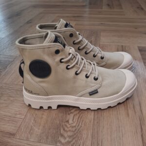 Pampa Hi Supply Affirmez votre style avec la nouvelle boot mi-haute Pampa Hi  Supply, une version revisitée de la Pampa Hi emblématique. Repensée cette saison avec une tige en 100% coton bio et des élements en caoutchouc recyclé, elle est idéale pour l’explorateur urbain respectueux de l’environnement. Ce modèle affiche un logo sur un patch en caoutchouc et des détails militaires au niveau du talon pour un look rétro. Un liseré brodé contrastant ajoute une touche colorée contrastée à ce modèle décontracté. La marque Palladium est une marque française qui propose depuis quelques décennies des chaussures en toile et en caoutchouc résistantes et durables. Avec des origines militaires et une forme bien reconnaissable, les Palladium traversent les générations sans prendre une ride (ou presque). Palladium est une marque française créée en 1920. À l'origine, son activité est bien différente de celle que l'on connait aujourd'hui : Palladium fabriquait des pneus pour l'aviation. La société fournissait alors la plupart des flottes aériennes européennes grâce à un procédé industriel unique : la vulcanisation du caoutchouc et de la toile. Au lendemain de la Seconde Guerre Mondiale, Palladium cesse peu à peu cette activité. En 1947, la société ouvre une usine à Pont de Cheruy, dans l'Isère, où elle commence à produire des chaussures selon le même principe de vulcanisation. Chaussures qui se révéleront tout aussi solides ! Le modèle emblématique de la marque est le "Pampa" qui équipe notamment la légion étrangère française