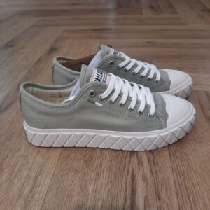 Palla Ace Canvas Kaki La sneaker Palla Ace Canvas Kaki rend hommage à notre héritage et à notre histoire avec l’univers du sport à travers une semelle extérieure en losange agrandi, inspirée de la célèbre bande de losanges des boots Pampa. Fier clin d’œil à nos racines françaises, elle arbore un drapeau tricolore sur le côté. Fabriquée en toile délavée douce et en coton bio, la Palla Ace Canvas Organic offre confort et durabilité, tandis que son bout caoutchouc protecteur et sa semelle extérieure assurent une aisance au quotidien. À la fois élégante et respectueuse de l’environnement, cette sneaker vous accompagne en toute confiance à chacun de vos pas, en alliant tradition et valeurs modernes. La marque Palladium est une marque française qui propose depuis quelques décennies des chaussures en toile et en caoutchouc résistantes et durables. Avec des origines militaires et une forme bien reconnaissable, les Palladium traversent les générations sans prendre une ride (ou presque). Palladium est une marque française créée en 1920. À l'origine, son activité est bien différente de celle que l'on connait aujourd'hui : Palladium fabriquait des pneus pour l'aviation. La société fournissait alors la plupart des flottes aériennes européennes grâce à un procédé industriel unique : la vulcanisation du caoutchouc et de la toile. Au lendemain de la Seconde Guerre Mondiale, Palladium cesse peu à peu cette activité. En 1947, la société ouvre une usine à Pont de Cheruy, dans l'Isère, où elle commence à produire des chaussures selon le même principe de vulcanisation. Chaussures qui se révéleront tout aussi solides ! Le modèle emblématique de la marque est le "Pampa" qui équipe notamment la légion étrangère française