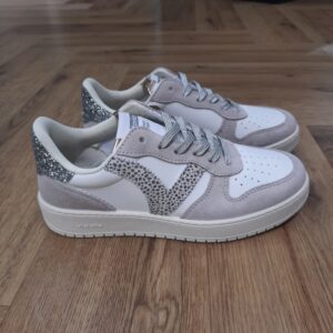 Madrid Léopard Silver Conçues par la célèbre marque Victoria, ces sneakers Madrid Léopard Silver s'adaptent parfaitement au style féminin moderne, alliant confort et tendance. Effectivement, chaque détail est soigneusement pensé pour offrir une expérience de port agréable tout au long de la journée. Fabriquées à partir de matériaux de qualité, ces baskets promettent durabilité et résistance. De plus, la semelle, conçue pour assurer une adhérence optimale, permet d'évoluer aisément sur différents types de surfaces. Ces sneakers sont adaptées que ce soit en milieu urbain ou lors de promenades en plein air. La marque Victoria est une marque qui a vu le jour en 1915 en Espagne. Le fondateur de la marque a commencé l'aventure avec une petite tennis qu'il a nommée comme sa femme adorée. Les chaussures Victoria ont évolué avec le temps bien sûr mais la marque s'évertue à conserver son ADN. Les Victoria évoluent et se parent de nouvelles couleurs, de matières originales ou d'imprimés, mais la base de la chaussure reste la même pour le plus grand plaisir des fans de la première heure. Les designers proposent de vastes collections chaque année qui renouvelle l'essence de Victoria ce qui lui permet de rester parmi les marques favorites des Espagnoles.