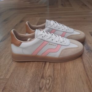 Gant Cuzima Cream La chaussure Gant Cuzima Cream est une paire de baskets d'inspiration rétro, qui se porte en toute saison. Tout d'abord, elles sont dotées d'une tige en cuir de qualité supérieure. De plus, elles arborent des finitions de couleur contrastante au niveau du bout, du talon et sur le côté. Puis, sa fine semelle extérieure en caoutchouc et la doublure en coton éponge apportent un style vintage à l'ensemble. Les baskets Gant Cuzima pour femme sont la fusion parfaite entre style rétro et confort. Avec leur design intemporel et leurs matériaux de qualité supérieure, elles sont idéales pour toute occasion. Elles garantissent un look décontracté et moderne qui ne passera pas inaperçu. La marque Quand Bernard Gant, un immigrant ukrainien, arrive à New-York en 1914, il se plonge directement au cœur des métiers du prêt-à-porter. Il travaille dans un atelier de confection de chemises dans le centre de la ville. Ce n'est que quelques années plus tard, alors qu'il a déménagé à New Haven dans le Connecticut qu'il lancera l'entreprise familiale à l'aide de sa femme, également dans le métier. Rapidement, il fabrique des chemises pour les plus grandes marques du pays tel que Brooks Brothers. Si le style de Gant a beaucoup évolué au cours des années, il ne s'est jamais vraiment détaché de son image de marque Américaine traditionnelle. En effet, adepte du style Ivy avec comme produit phare la chemise à col boutonné. Après avoir été suédoise, la marque a été rachetée en 2008 par le groupe suisse Maus Frères, qui détient entre autres Lacoste et Aigle, mais elle garde encore ses valeurs originelles : celles de Bernard Gant.