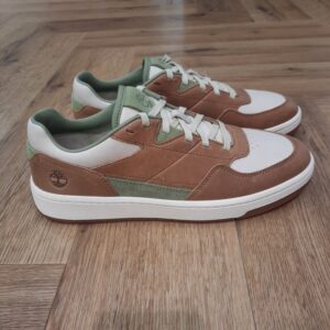 Timberland Jackson Court La basket Timberland Jackson Court est un classique inspiré des courts de tennis, revisité avec élégance. Le cuir Premium Timberland® Leather et la silhouette épurée de cette basket polyvalente lui confèrent une allure sobre. Sa doublure en toile ReBOTL™ contient au moins 50 % de plastique recyclé, son assise plantaire OrthoLite® assure un amorti et un confort optimaux, et sa semelle extérieure en caoutchouc résistant garantit une adhérence parfaite. Portez-la avec un chino pour un look chic ou avec un jean pour un style décontracté. Élégante, confortable et conçue pour durer. L’histoire de Timberland L’histoire des Timberland Boots remonte à la ville de Newmarket, dans le New Hampshire, aux États-Unis, où elles ont été créées en 1973. À l’origine, elles étaient destinées aux travailleurs du bâtiment et des espaces extérieurs. Les fondateurs, Nathan Swartz et sa famille, ont mis l’accent sur la qualité et la durabilité dès le départ. C’est ainsi que les premières Timberland Boots sont nées, dotées de coutures étanches, d’une semelle crantée pour une meilleure adhérence, et d’un cuir de première qualité. Cette combinaison de caractéristiques en a rapidement fait des chaussures de choix pour les travailleurs et les amateurs de plein air. Au fil des années, les Timberland Boots ont conquis un public plus large. Elles sont devenues un élément essentiel du style urbain, notamment dans le mouvement hip-hop des années 90, où elles ont été adoptées comme symbole de résilience et de style. Le nom « Timberland » lui-même évoque des images de forêts, de montagnes et d’aventures en plein air, ce qui en fait un choix idéal pour les esprits aventuriers.