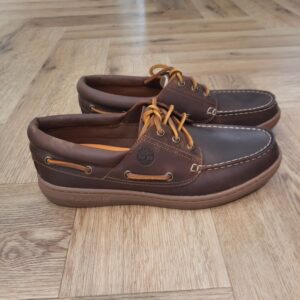 Timberland Portofino Marron La chaussure bateau Timberland Portofino Marron pour homme allie style nautique intemporel et confort moderne. D'abord, elle est confectionnée en cuir Premium Timberland® Leather. Puis, elle est dotée d’une doublure en daim synthétique doux, d’une assise plantaire OrthoLite® rembourrée. De plus, elle possède une semelle extérieure en caoutchouc rainuré pour une adhérence fiable sur les surfaces humides ou sèches. En effet, en achetant ce produit, vous soutenez les tanneries certifiées par le Leather Working Group. L’histoire de Timberland L’histoire des Timberland Boots remonte à la ville de Newmarket, dans le New Hampshire, aux États-Unis, où elles ont été créées en 1973. À l’origine, elles étaient destinées aux travailleurs du bâtiment et des espaces extérieurs. Les fondateurs, Nathan Swartz et sa famille, ont mis l’accent sur la qualité et la durabilité dès le départ. C’est ainsi que les premières Timberland Boots sont nées, dotées de coutures étanches, d’une semelle crantée pour une meilleure adhérence, et d’un cuir de première qualité. Cette combinaison de caractéristiques en a rapidement fait des chaussures de choix pour les travailleurs et les amateurs de plein air. Au fil des années, les Timberland Boots ont conquis un public plus large. Elles sont devenues un élément essentiel du style urbain, notamment dans le mouvement hip-hop des années 90, où elles ont été adoptées comme symbole de résilience et de style. Le nom « Timberland » lui-même évoque des images de forêts, de montagnes et d’aventures en plein air, ce qui en fait un choix idéal pour les esprits aventuriers.